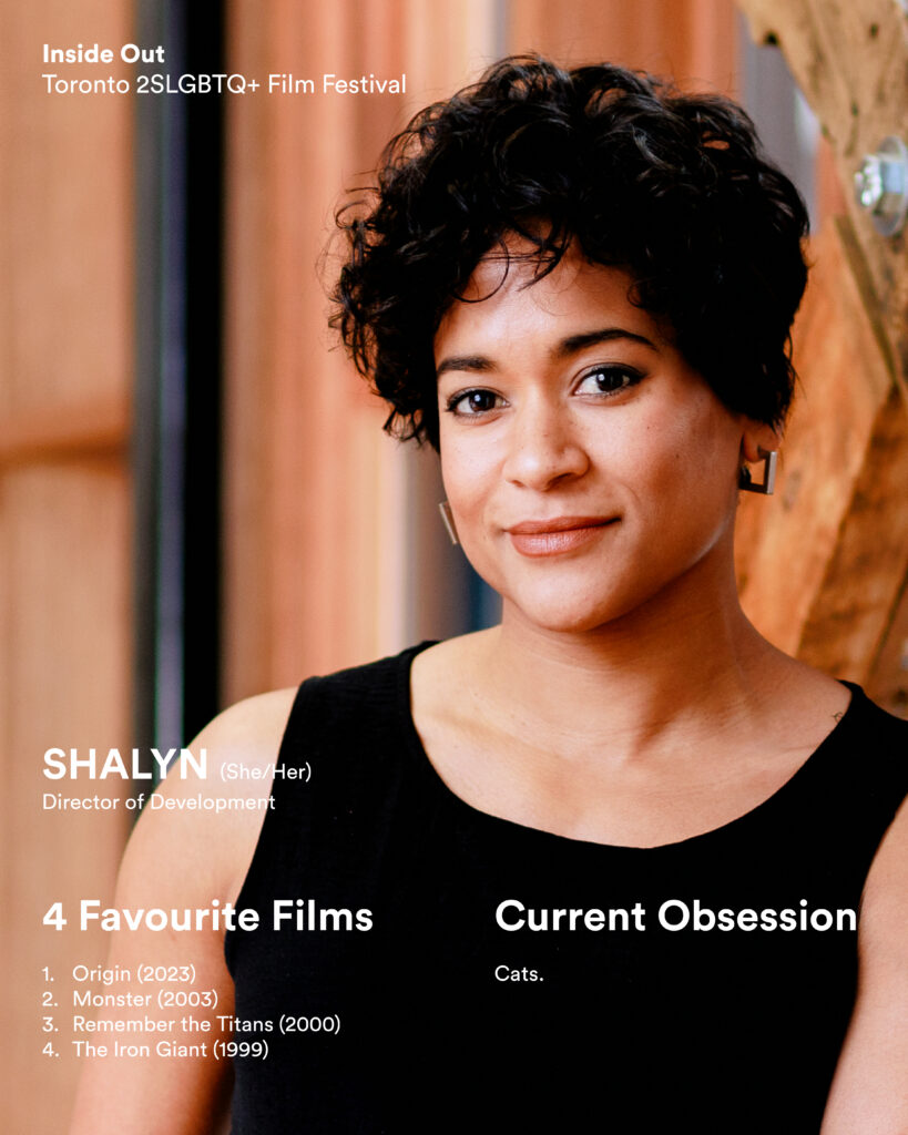 A woman with short curly hair and hoop earrings smiles at the camera.