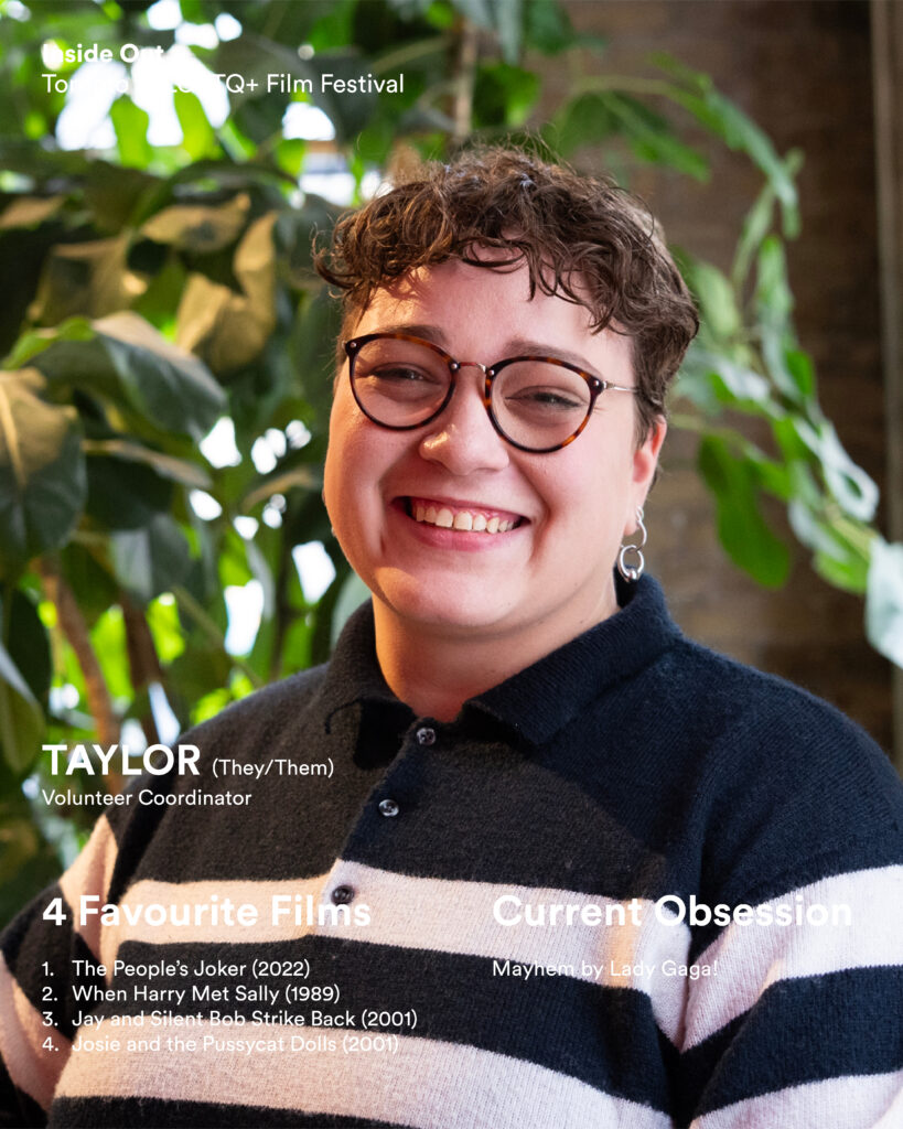 A person with short curly hair, round glasses, and a striped sweater smiles at the camera.