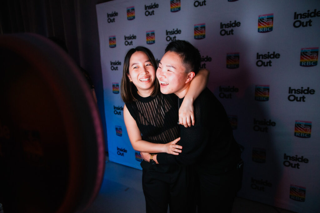 Two people in black outfits smile and hug each other while posing for a photo in front of a step-and-repeat backdrop featuring "Inside Out" and RBC logos.