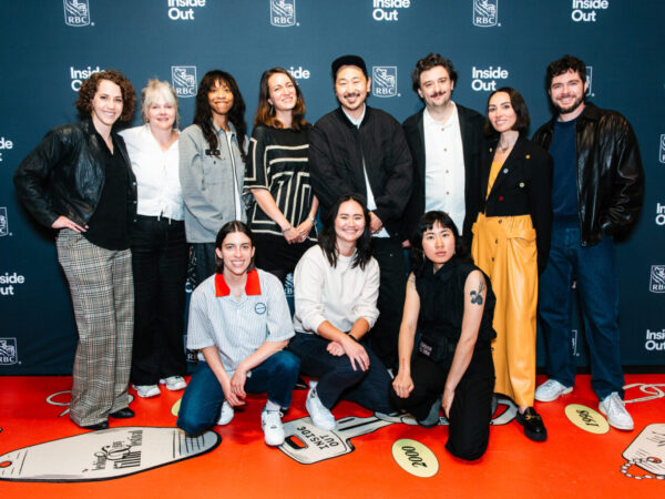 A group of eleven people pose together, smiling, in front of a blue backdrop with "Inside Out" and "RBC" logos. Some are standing, others are kneeling, dressed in casual and semi-formal attire.